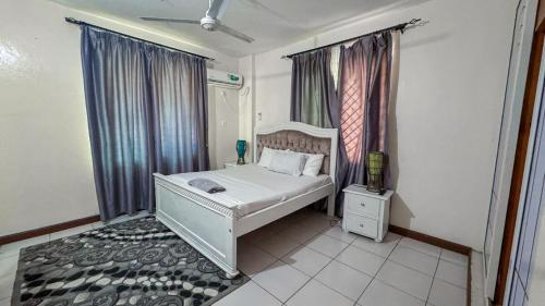 a bedroom with a white bed and a window at The Rosebay Apartment in Mombasa