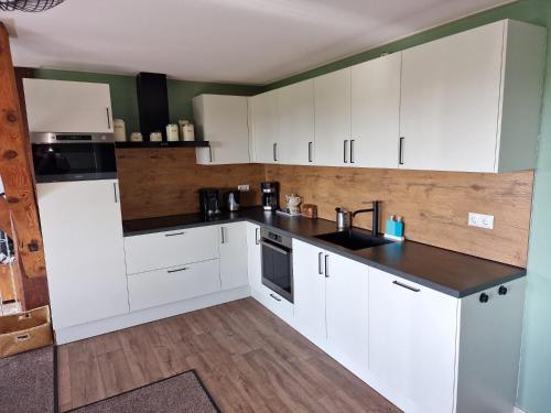 a kitchen with white cabinets and a black counter top at Tussen Wad en Dijk - Vakantieappartement in Sint Jacobiparochie