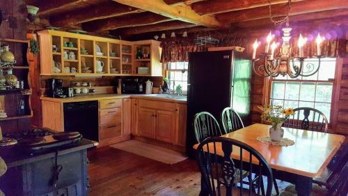 a kitchen with a table and a black refrigerator at Deer Valley Retreat, Lovely Log Cabin with Fireplace & Garden Views- Perfect for a Relaxing Getaway! in Bradford