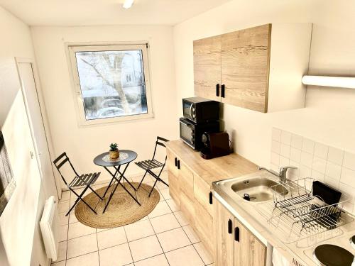 une petite cuisine avec un évier et une table dans l'établissement L Archipel Le Mans Est Pontlieue, au Mans