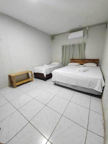 a room with two beds and a tiled floor at Pousada Cactus in Barreirinhas