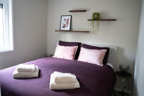 Una cama morada con dos toallas encima. en Luxe chalet 5p met hottub midden in het bos - Boshuisje Casa Kuin, en Haarle