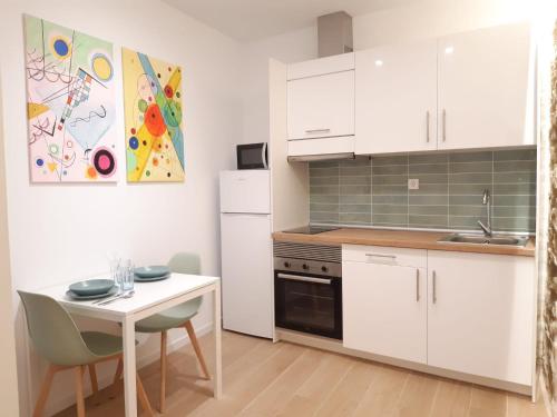 une cuisine avec des armoires blanches et une petite table blanche et un réfrigérateur blanc dans l'établissement Good Energy Rooms, à Alicante