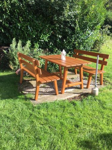 two benches and a wooden picnic table in the grass at Ferienhaus Edelweiss in Schüpfheim