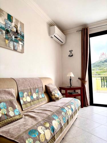 a living room with a couch and a window at Mellieha Seaside Apartment in Mellieħa
