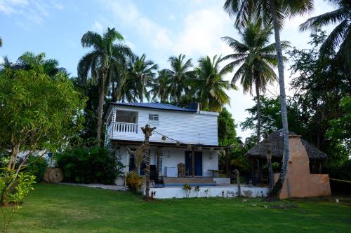 a white house with palm trees in a yard at villas ecologicas hacienda vista linda in Cabrera
