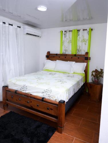 a bedroom with a wooden bed with green accents at villas ecologicas hacienda vista linda in Cabrera