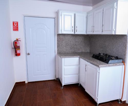 a small kitchen with white cabinets and a stove at villas ecologicas hacienda vista linda in Cabrera