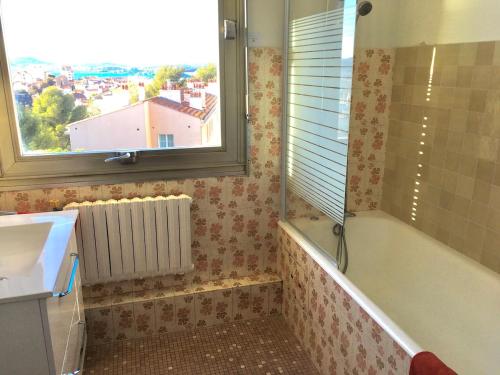 une salle de bain avec une baignoire, un lavabo et une fenêtre dans l'établissement Le Goéland, à Toulon
