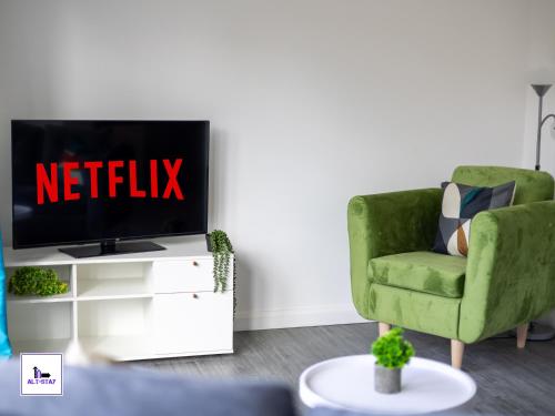 a living room with a green chair and a tv at Temple by Alt-Stay Contractor Accommodation - 4 Bed Contractor Home With Parking, Wi-Fi & Full Kitchen - Ideal For Long stays in Leeds