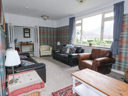 a living room with leather furniture and a large window at Callart View in Ballachulish