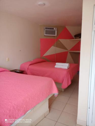 two beds in a room with pink sheets at Villa kosniin in Tecolutla