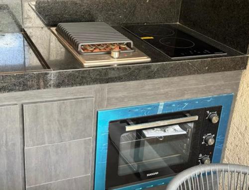 a kitchen with a counter with a stove and a microwave at Casa en Milagres com piscina 600 metros da praia in São Miguel dos Milagres