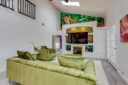 a living room with a green couch and a tv at Pop Art Oasis with Karaoke Mini Golf Hot Tub and Pool in Arvada