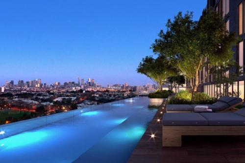 a swimming pool with a view of a city at night at Luxe Flemington Cityscape Racecourse views Pool Gym Parking in Melbourne