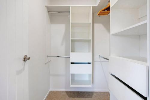 a walk in closet with a glass door and shelves at Spacious Modern Home near Airport and Manukau City in Auckland