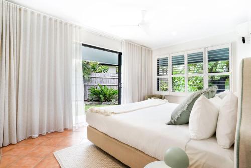 a white bedroom with a large bed and a window at Casa Del Sol Palm Cove in Palm Cove