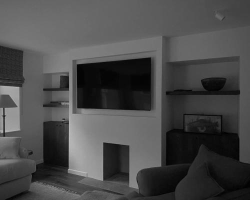 een woonkamer met een flatscreen-tv boven een open haard bij Old school - Charming Historic Cottage for Seven in Ballater