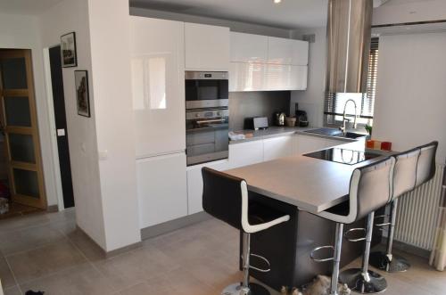 une cuisine avec des armoires blanches et une table et des chaises dans l'établissement Agréable 2p entre Antibes et Juan les Pins, à Antibes