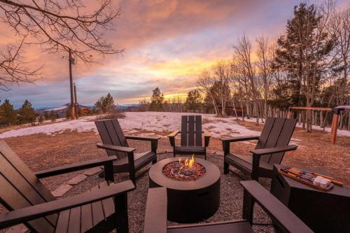a fire pit with three chairs and a table with a fire burns at The Aspen Ridge Stargazer in Cripple Creek