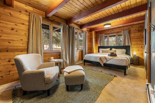 a bedroom with a bed and a chair and windows at The Aspen Ridge Stargazer in Cripple Creek