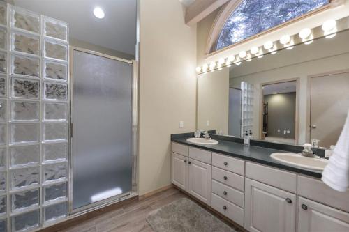 Un baño con dos lavabos, una ducha y un espejo. en Trailside Mountain Retreat with Private Hot Tub, en Winter Park