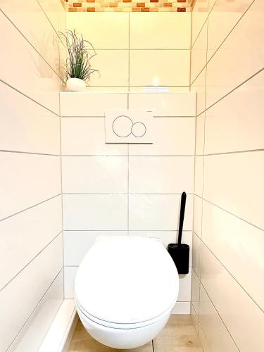 a white toilet in a bathroom with white tiles at Duhnerherz Bestlage im Zentrum,am Strand Duhnen, Balkon mit Meerblick,Wlan Parkplatz und Fahrradabstellraum Bettwäsche und Handtücher inkl in Cuxhaven