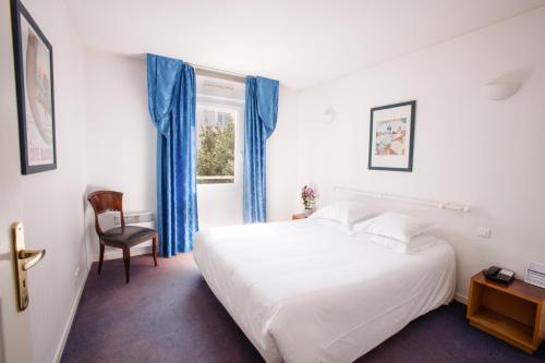a bedroom with a white bed and blue curtains at Résidence Biarritz Ocean in Biarritz