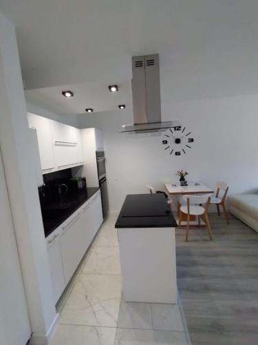 a kitchen with white cabinets and a table in a room at MG Apartament Elfów in Tychy