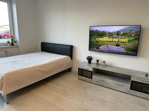 a bedroom with a bed and a flat screen tv on the wall at KOMFORT FerienWohnung NeuBau Merzig in Merzig