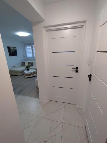 a hallway with a white door and a living room at MG Apartament Elfów in Tychy