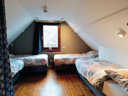 a attic room with two beds and a window at Le havre du lac in Vielsalm
