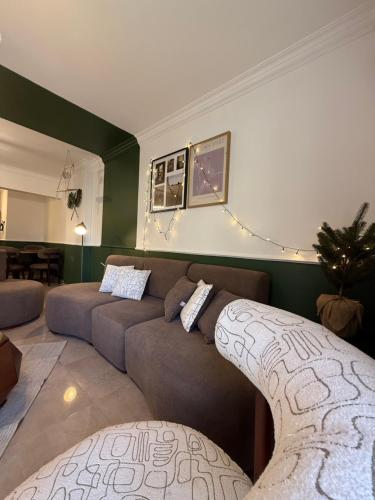 a living room with a brown couch and a living room with green walls at JRE-EG modern aprt01SheikhZayed 5min to ArkanPlaza in Sheikh Zayed
