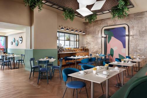 a dining room with tables and blue chairs at The Spring House Hotel Rome Vatican, Tapestry Collection Hilton in Rome