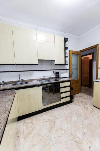 a large kitchen with white cabinets and marble floors at Casa Javi in Ojedo