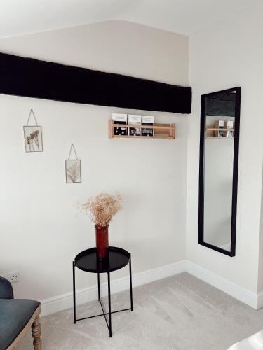 a living room with a table and a mirror at The Potting Shed in Chepstow