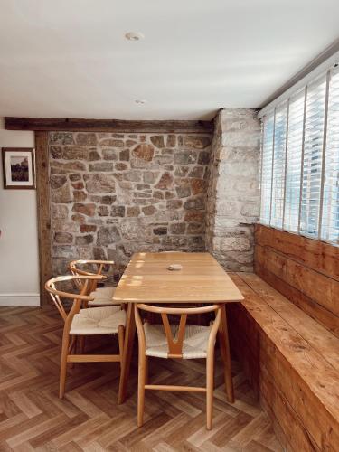 a wooden table and chairs in a room with a brick wall at The Potting Shed in Chepstow