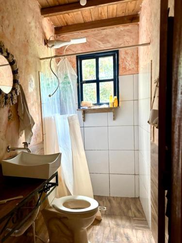 a bathroom with a toilet and a sink and a window at Vila Alamandra in Ibicoara