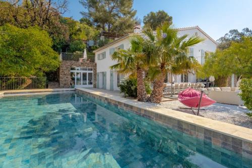 une grande piscine avec un palmier et une maison dans l'établissement Villa Romarine, à Rayol-Canadel-sur-Mer