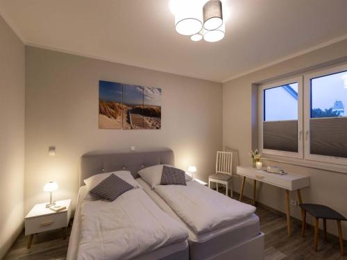 a bedroom with a bed and a desk and a window at Exclusives Appartement auf Fehmarn in Petersdorf auf Fehmarn