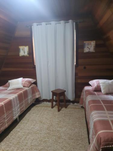 a bedroom with two beds and a white curtain at Chalé Schueler in Nova Friburgo