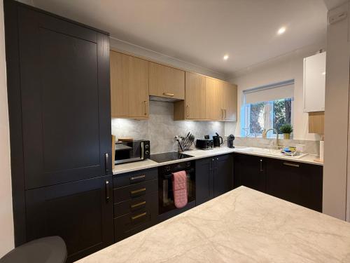 a kitchen with black cabinets and a sink at In the heart of the Town centre Ringwood, New Forest - Star Cottage in Ringwood