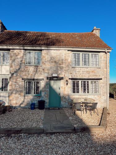 ein Steinhaus mit einer grünen Tür und einem Tisch in der Unterkunft Gardener's Cottage in Chepstow