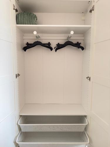 a closet with two black hangers in it at Duhnerherz Bestlage im Zentrum,am Strand Duhnen, Balkon mit Meerblick,Wlan Parkplatz und Fahrradabstellraum Bettwäsche und Handtücher inkl in Cuxhaven