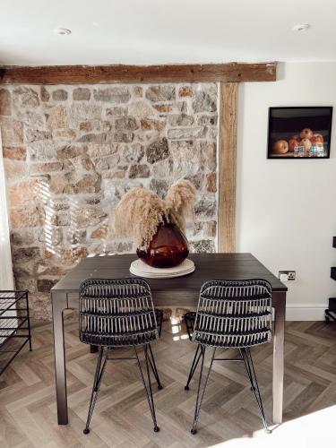 a table with two chairs and a vase on it at Gardener's Cottage at Mathern Palace in Chepstow