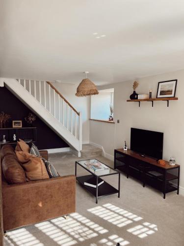 ein Wohnzimmer mit Sofa und Fernseher in der Unterkunft Gardener's Cottage in Chepstow