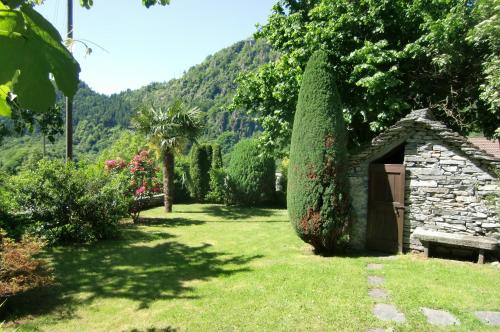 un jardín con un banco y un cobertizo de piedra en Fienile en Avegno