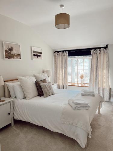 une chambre blanche avec un grand lit et une fenêtre dans l'établissement Gardener's Cottage, à Chepstow