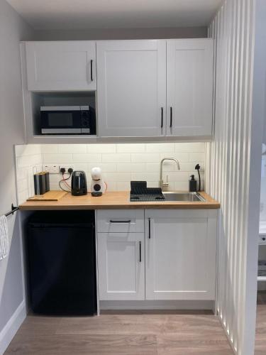 a small kitchen with white cabinets and a sink at Kinvara Guest Suite in Galway