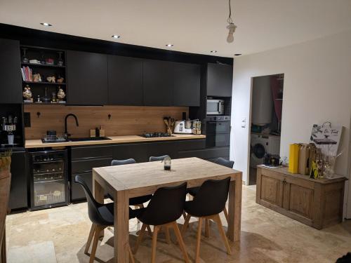 une cuisine avec une table en bois et des armoires noires dans l'établissement charmante petite maison - piscine hors sol - proche Avignon, à Avignon